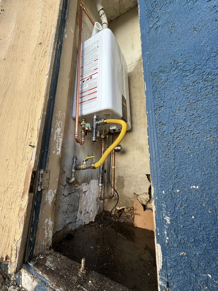 Tankless water heater mounted in an exterior alcove with new copper and a yellow flex gas line