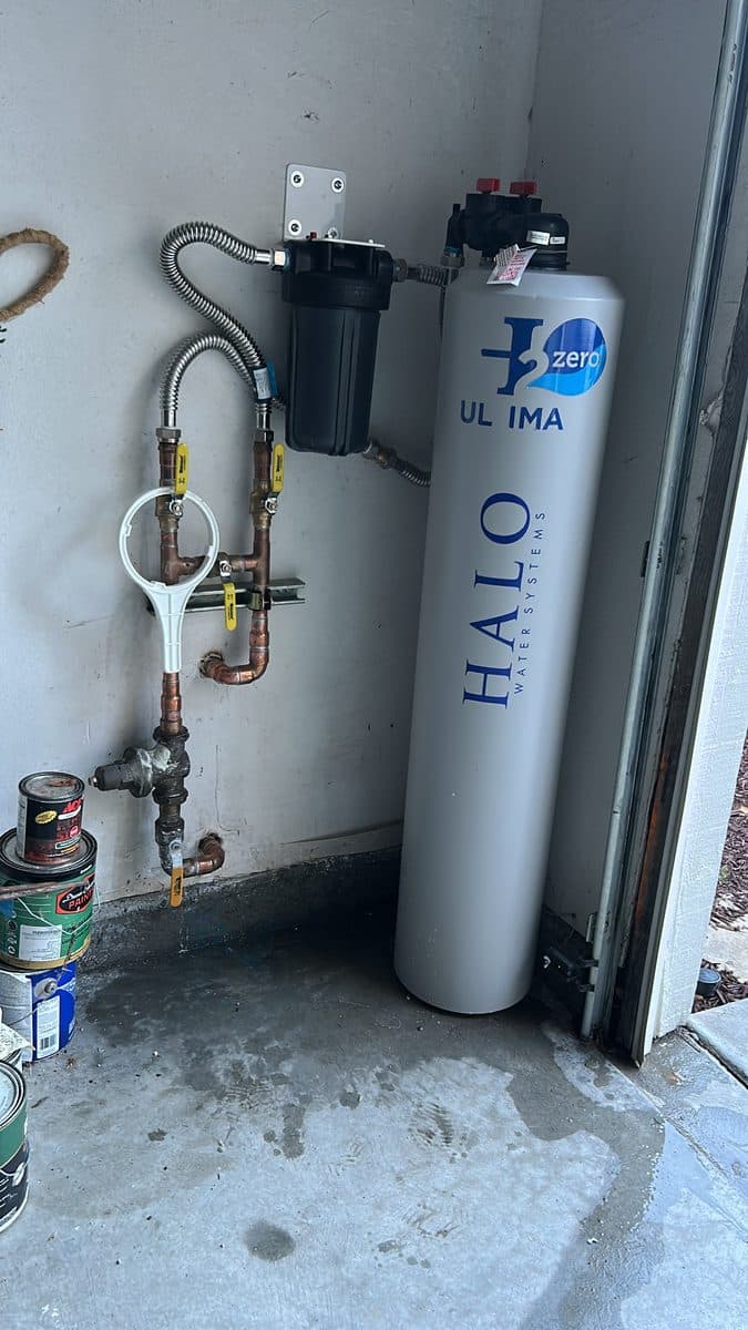 Whole-house water filtration system installed in a garage corner with copper and shutoff valves
