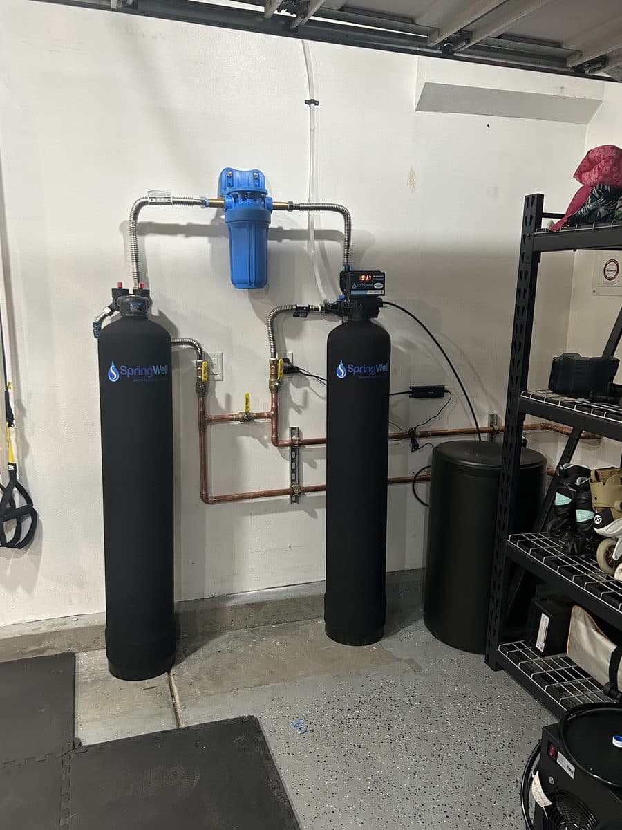 Whole-house water filtration and softener tanks plumbed with a copper manifold in a garage